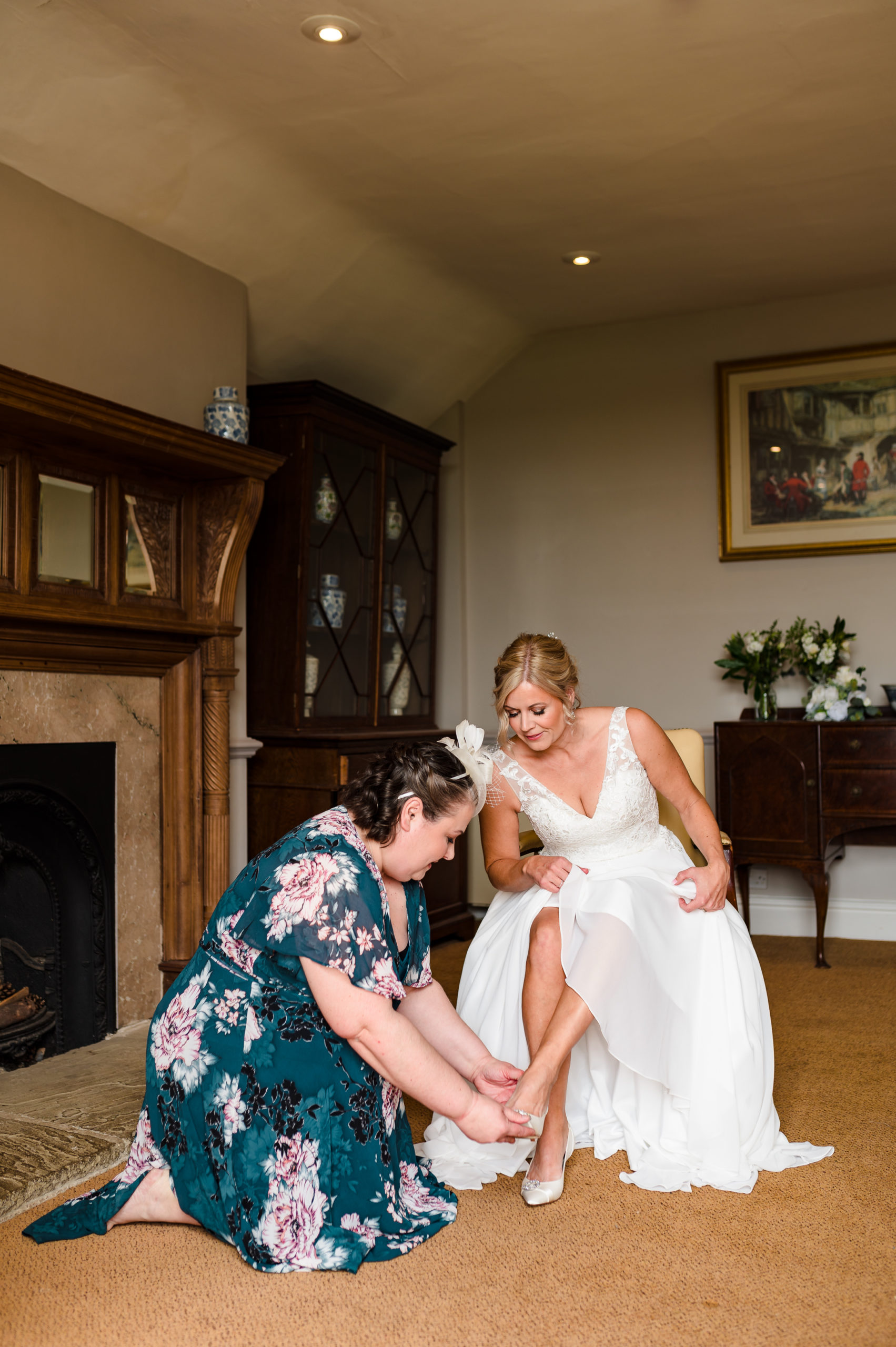 brides sister putting on her wedding shoes