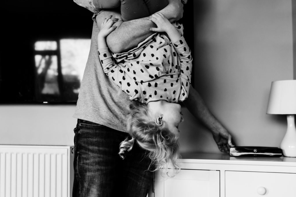 Girl being carried upside down by her dad
