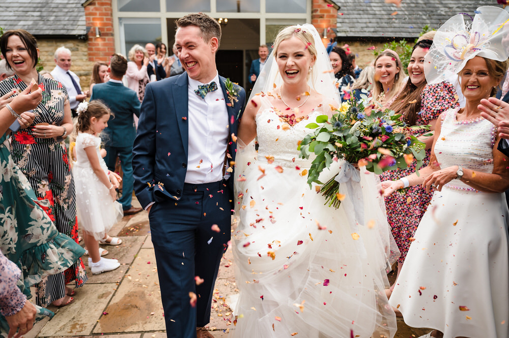 bride and groom walking through confetti at rutland water golf course